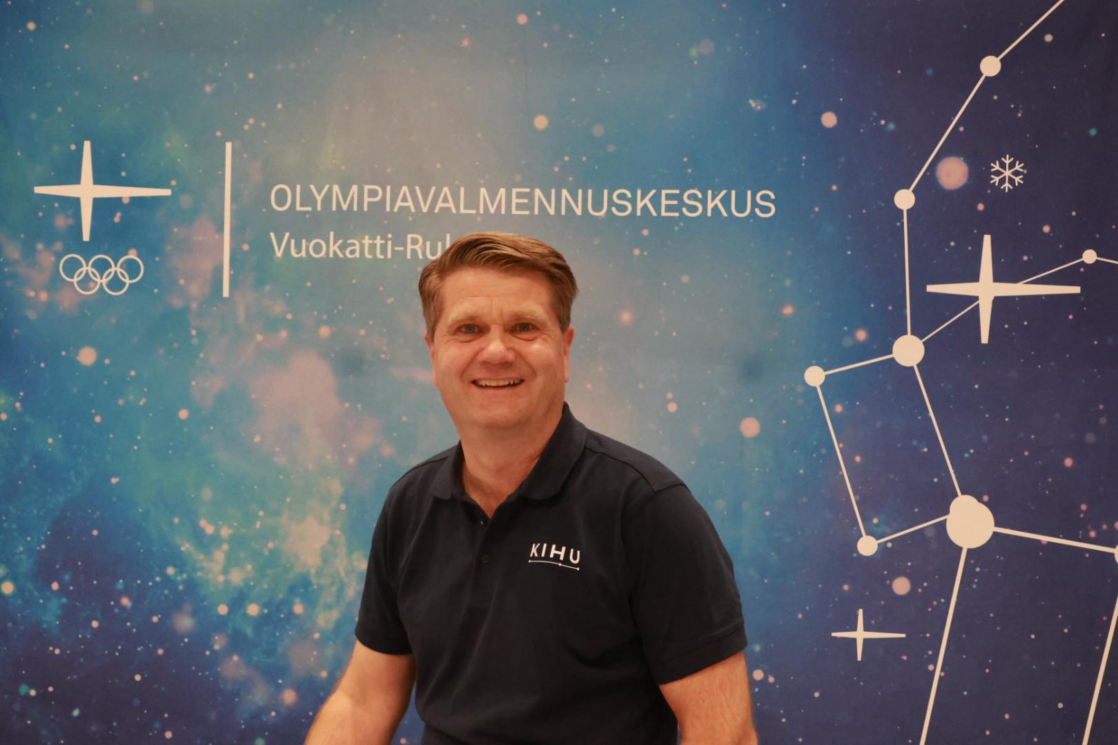 KIHU:n toimitusjohtaja Arto Kuusisto Olympiavalmennuskeskus Vuokatti-Rukan seinän edessä.