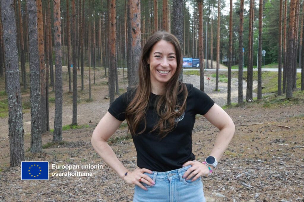 Liiketoiminnan kehittäjä Jenni Strengell seisoo Vuokatin mäntymetsässä hymyillen.