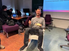 Kuvassa Jussi Piirainen istuu keinutuolissa ja syö kakkua.